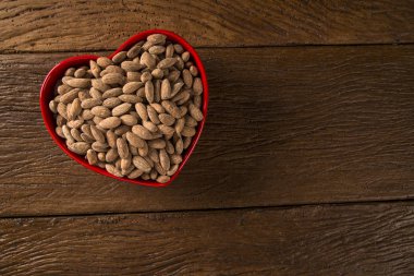 Badem ahşap arka plan üzerinde bir kalp kap içinde