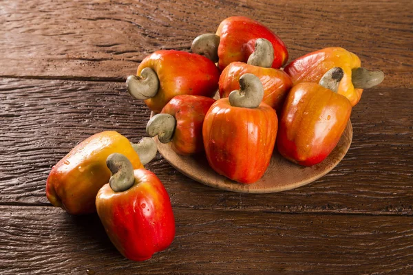 Some cashew fruit over a wooden surface.