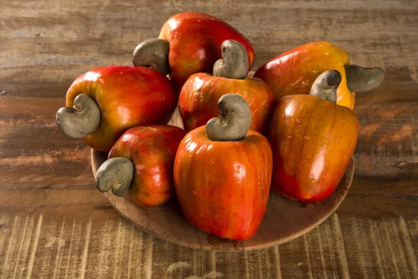 Some cashew fruit over a wooden surface.