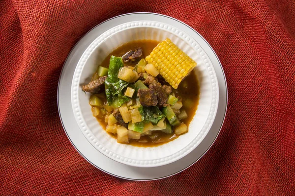South American cuisine: Puchero soup with chickpeas close-up in a pot on the table.
