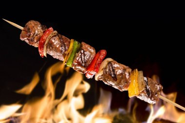 Bir yangın arka planda sebzeli et şiş