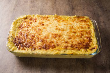 Bol patates graten jambon ve parmesan peyniri ile krem ve lezzetli kurutulmuş domuz pastırması South Tyrol üzerinden taze fırın ahşap bir masa üzerinde ye kadar devam eder