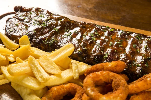 Barbecue varkensribbetjes met patat en uienringen — Stockfoto