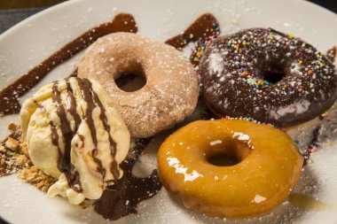 lezzetli tatlı çörek ve dondurmayla dekorasyon ahşap bir masa üzerinde beyaz bir plaka üzerinde.