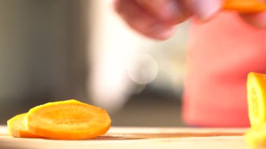 Ev bir mutfak ahşap doğrama tahtası üzerinde bir bıçakla bir havuç eller bir kadının bir bıçak ile kesmek. 