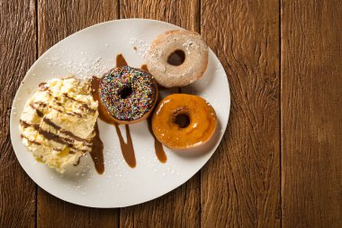 lezzetli tatlı çörek üzerinde ahşap bir masa dekorasyonu ile beyaz bir plaka üzerinde dondurma ile