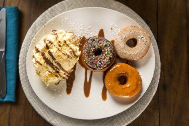 lezzetli tatlı çörek üzerinde ahşap bir masa dekorasyonu ile beyaz bir plaka üzerinde dondurma ile