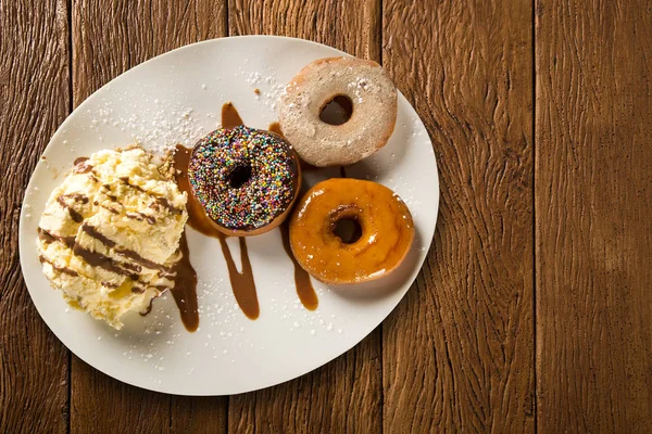 lezzetli tatlı çörek üzerinde ahşap bir masa dekorasyonu ile beyaz bir plaka üzerinde dondurma ile