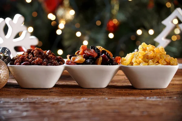 Raisins into a bowl on rustic old wooden table with christmas background — Stock Photo, Image