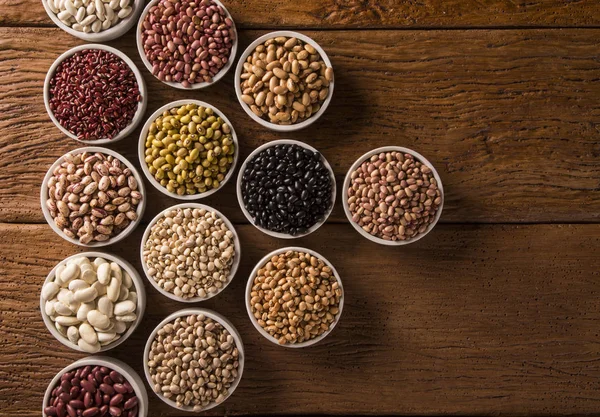 Fagioli assortiti in ciotole su fondo legno — Foto Stock