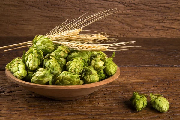 Ingrédients de la bière Cônes de houblon dans un bol en bois et épis de blé sur fond en bois. Concept de brasserie de bière — Photo