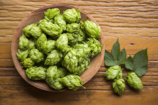 Bierbrauzutaten Hopfenzapfen in Holzschale und Weizenähren auf Holzgrund. Brauereikonzept — Stockfoto