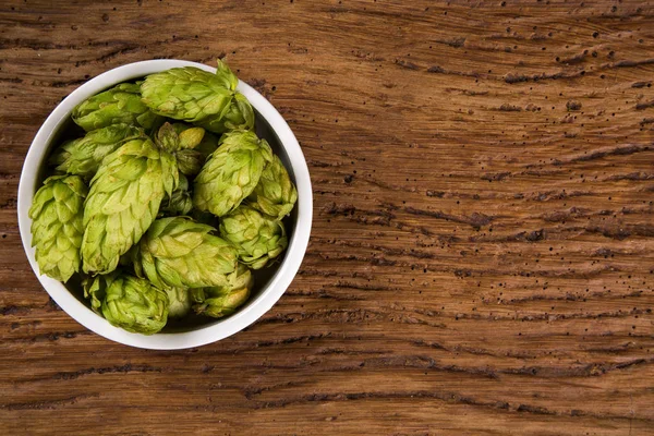 Ingrédients de la bière Cônes de houblon dans un bol en bois et épis de blé sur fond en bois. Concept de brasserie de bière — Photo