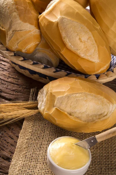Cesta de "pão francês", pão tradicional brasileiro com manteiga sobre fundo de madeira . — Fotografia de Stock