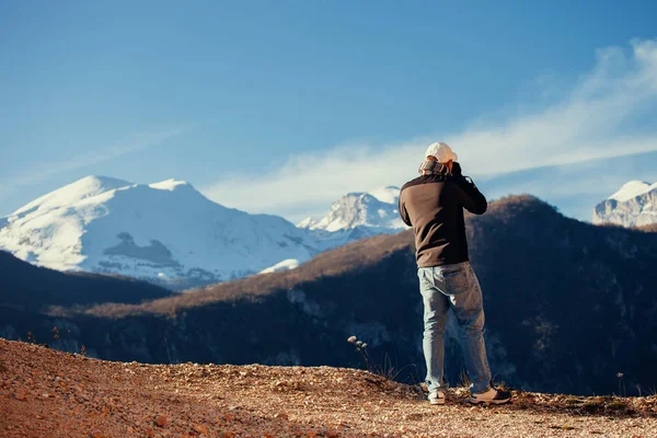 Pohledný muž cestovat v zimních horách s fotoaparátem — Stock fotografie