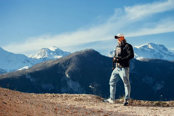 Bell'uomo viaggia in montagna d'inverno con macchina fotografica — Foto Stock