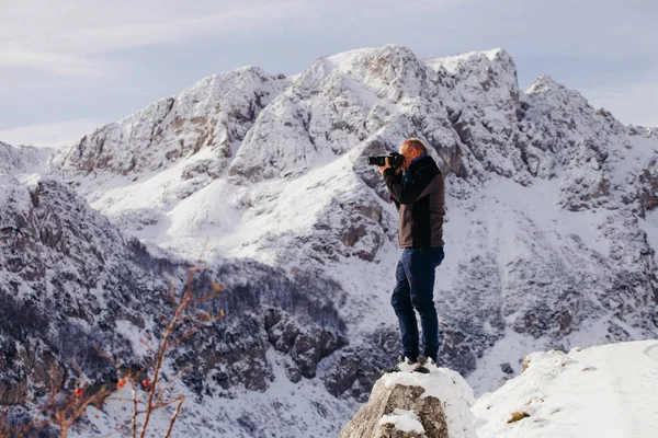 Bell'uomo viaggia in montagna d'inverno con macchina fotografica — Foto Stock