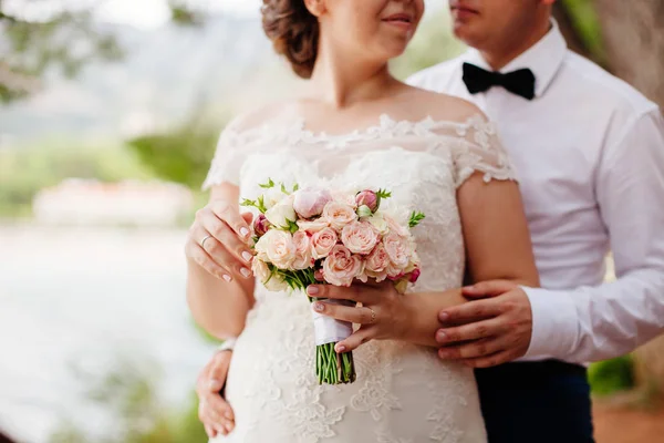 Recém-casados segurando buquê de casamento — Fotografia de Stock