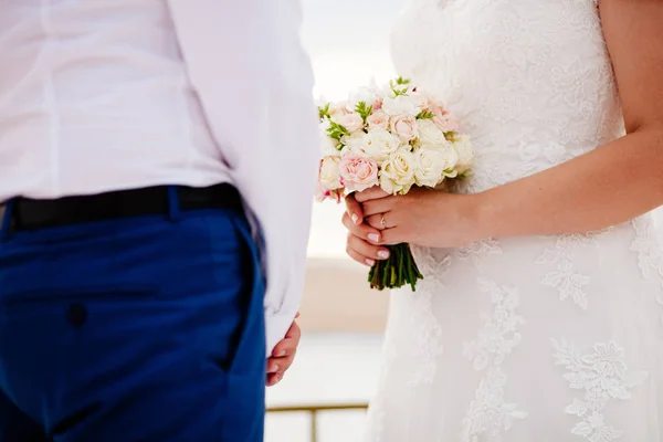 Recém-casados segurando buquê de casamento — Fotografia de Stock