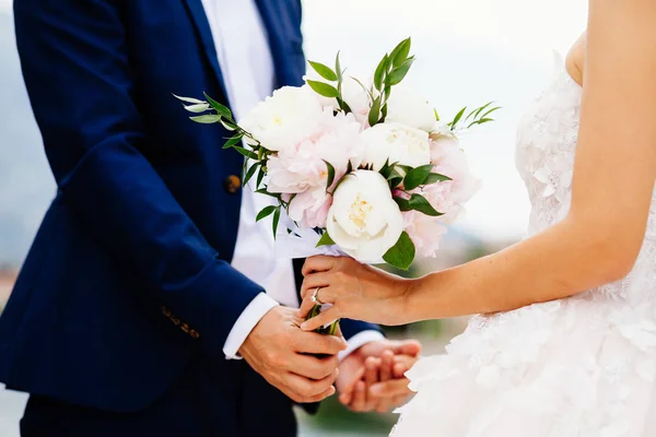 Bride and groom holding wedding bouquet together — Stock Photo, Image