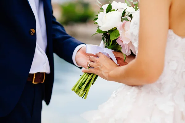 Noiva e noivo segurando buquê de casamento juntos — Fotografia de Stock