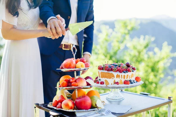 Nevěsta a ženich krájí svatební dort — Stock fotografie