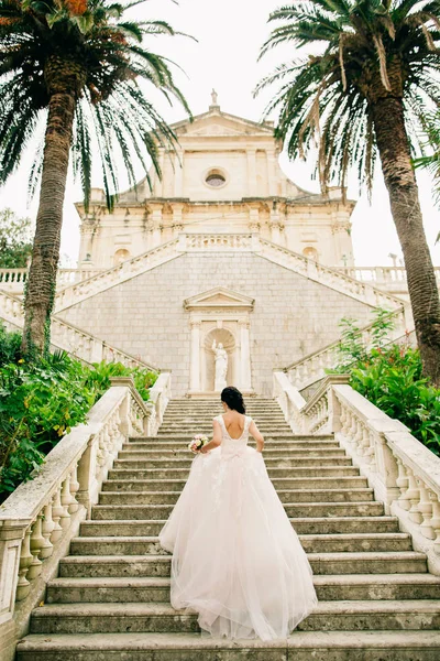 Nevěsta ve svatebních šatech s církevní pozadím — Stock fotografie