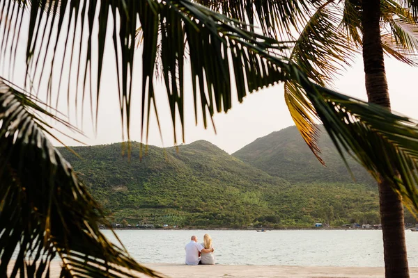 Pareja relajarse en la playa con palmeras — Foto de Stock