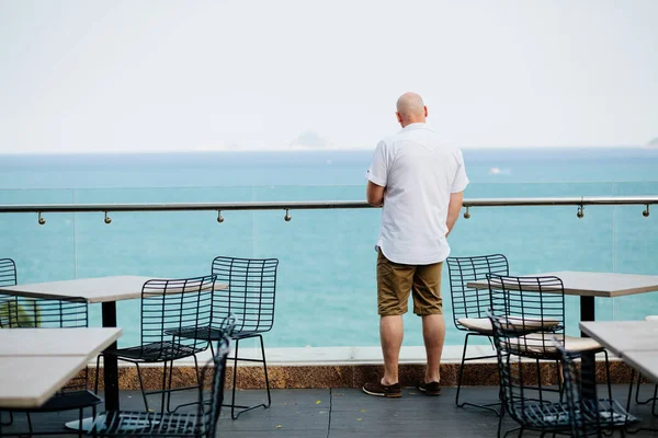 Uomo relax in caffetteria con vista mare — Foto Stock