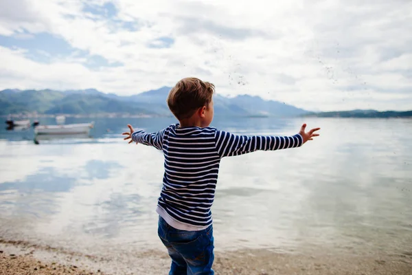 Boy throw stones in water — Stock Photo, Image