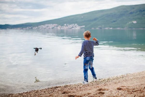 Niño tirar piedras en el agua — Foto de Stock