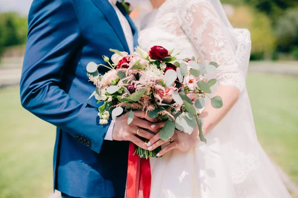 Gelin ve damat düğün buketi taşıyor.
