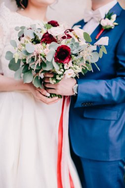 Gelin ve damat düğün buketi taşıyor.