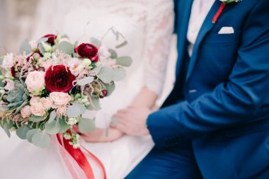 Gelin ve damat düğün buketi taşıyor.