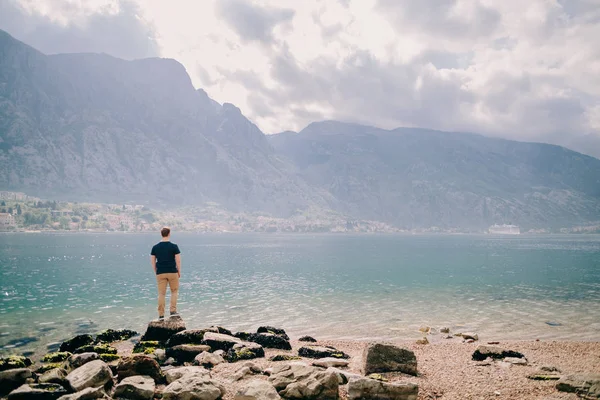 Adam seyahat kayalık plaj ve dağlar defne görünümü — Stok fotoğraf
