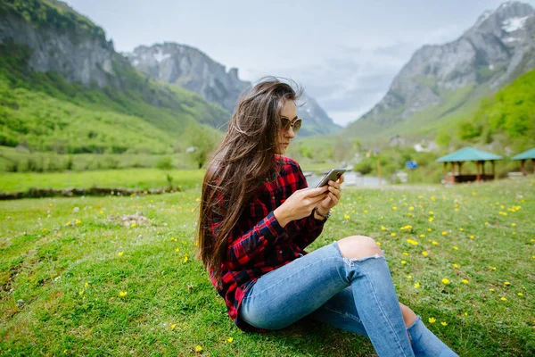 山でバックパックを背負ってのスマート フォンを持つ女性 — ストック写真