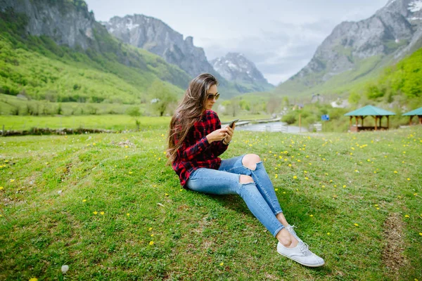 山でバックパックを背負ってのスマート フォンを持つ女性 — ストック写真