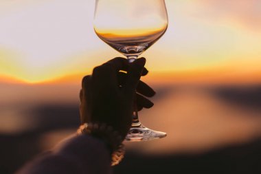 bardak şarap gün batımında. Bardak beyaz şarap tutan kadın.