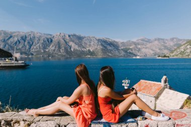 Dağ Manzaralı sahil üzerinde iki kız rahatlatıcı. Kotor Körfezi, Karadağ
