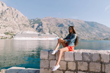 Karadağ'daki cruise gemi manzaralı sahilde oturan kadın. Kotor Körfezi.