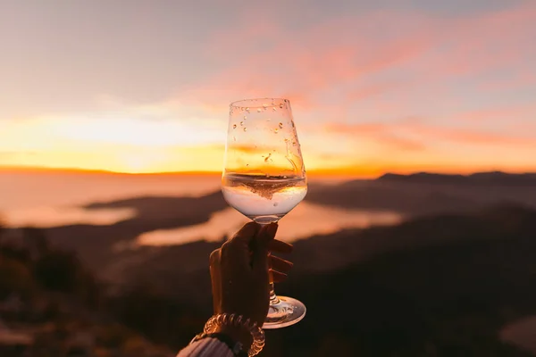 bardak şarap gün batımında. Bardak beyaz şarap tutan kadın.