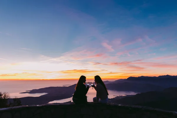 girls drinking wine  at sunset in mountains