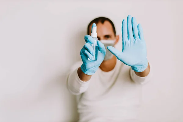 man using liquid hand sanitizer during quarantine at home. Caucasian male wearing face mask and using alcohol gel to clean hands and skin against virus, germs, bacteria for health care. Stay at home