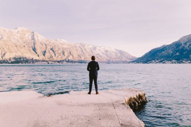 İş adamı dağlara ve körfeze bakıyor. Düşünmek ve karar vermek. Karadağ, Kotor Körfezi