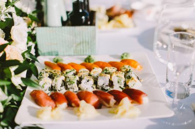 Restoranda suşi ruloları servis ediliyor. Restoranda suşi beyaz tabakta yuvarlanıyor..