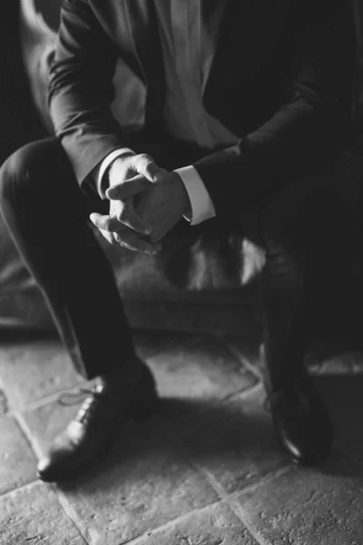 man sitting with hands on the knees and fingers locked. Business man nervous and waiting for decision. Black and white.