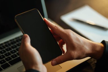 Ofis çalışanı telefonun fotokopisini çekiyor. İş adamı ofis çalışma alanında bitki ve kahve geçmişi olan telefon ve dizüstü bilgisayar kullanıyor. Siyah ekran aygıtları.
