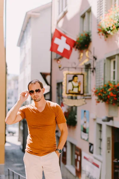 サングラスとシャツを着たハンサムな男が古い町の通りを歩いてる スイス チューリッヒを旅する スイス チューリッヒを旅する白人男性 — ストック写真