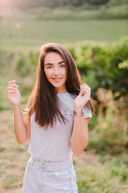 Yazın kırsal kesimde dinlenen kadın portresi. Kafkasyalı uzun saçlı kadın gün batımında kırsal üzüm bağlarında dinleniyor. İtalya