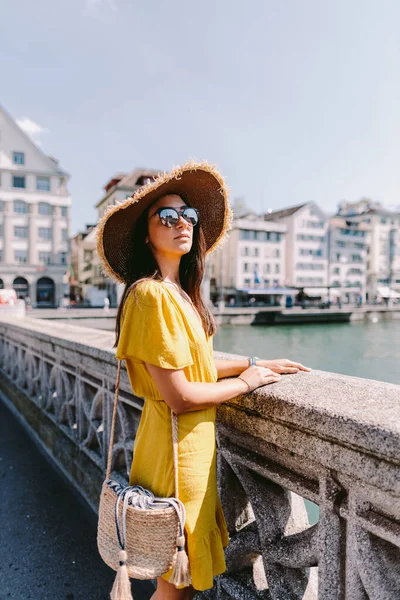 Avrupa 'da gezen moda kadını portresi. Yazlık elbise, şapka ve güneş gözlüğü takan bir kadın kameraya bakıyor. İsviçre, Zürih.